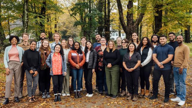 Switzer Fellows and staff at the 2023 Fall Retreat, standing in front of large trees and on a path littered with fall leaves.