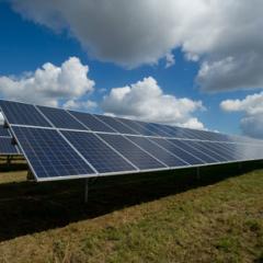 A field of solar panels against a background of blue sky and clouds