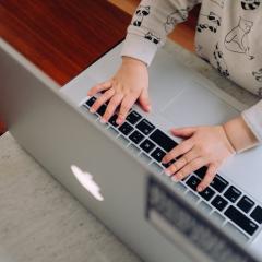 A toddler's hands appear to type on a laptop keyboard