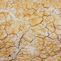 Cracks in dry brown, yellow and white soil.