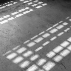 Light coming from the windows onto a concrete floor in an old building.