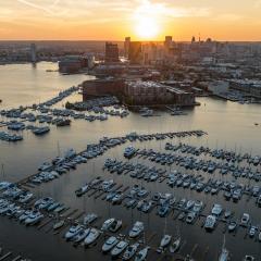 Sunshine over the Baltimore Harbor full of sailboats against an urban skyline. 