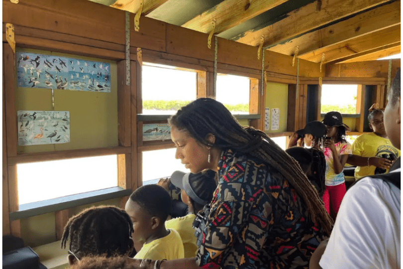 Olivia Walton stands with a group of students in a bird watching blind.