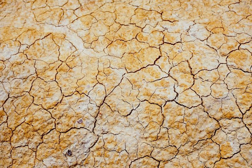 Cracks in dry brown, yellow and white soil.